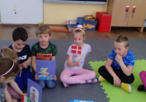 Dzieci trzymają flagę Danii i obrazek bajki z z tego kraju.
